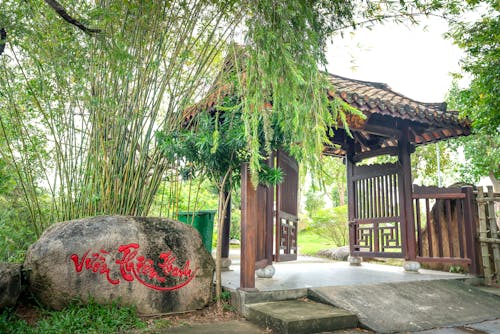 Wooden Gate and Bamboo Plant by a Stone with a Red Script