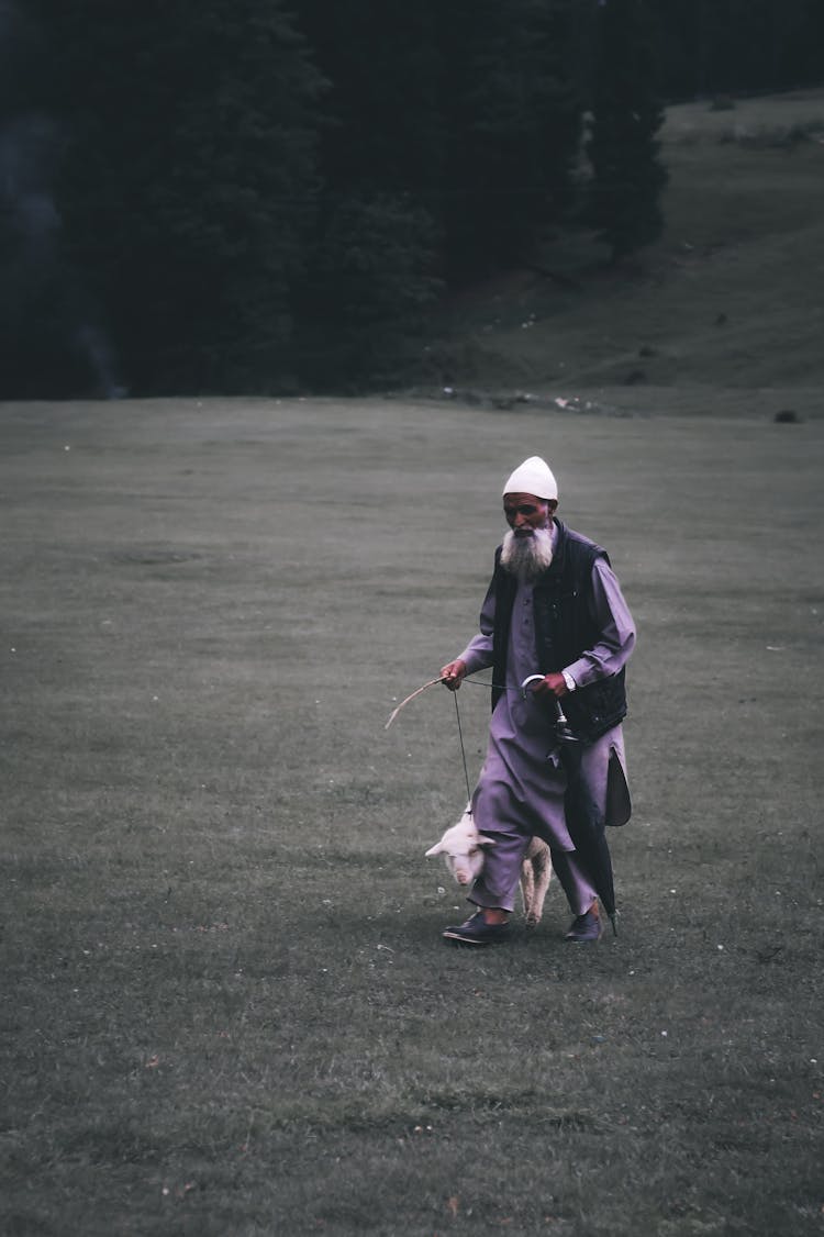 Man Walking On A Field With A Pig 