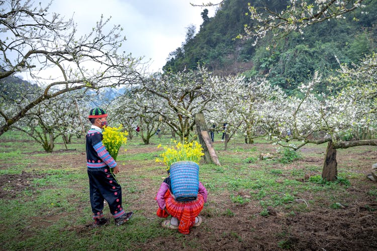 Teenager Couple In An Orchard Holding Flowers