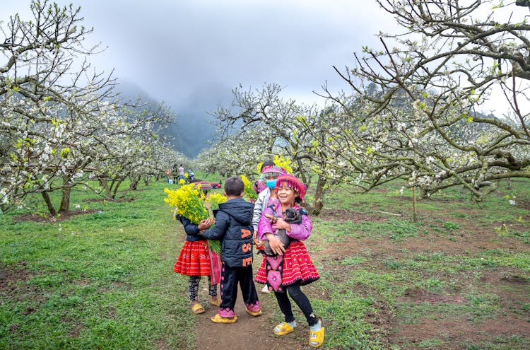 A Group Of Kids Standing Near The Trees 