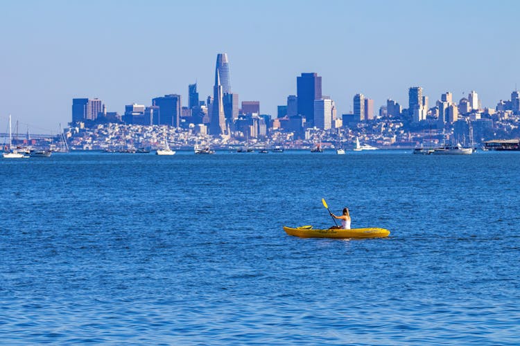 Woman Sailing In Boat With City Skyline On Background