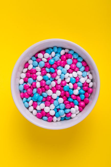 A white bowl filled with colorful candy against a vivid yellow background, perfect for food promotions.