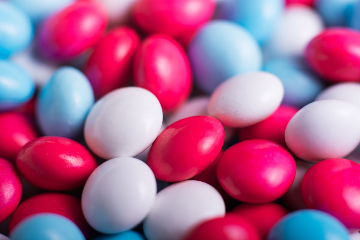 Vibrant close-up image of red, blue, and white candy coated chocolates with depth of field effect.