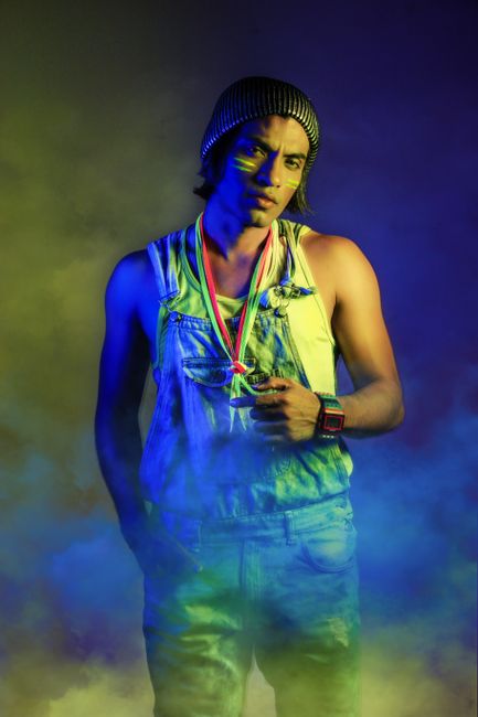 Colorful portrait of a man in denim overalls, surrounded by vibrant neon smoke.