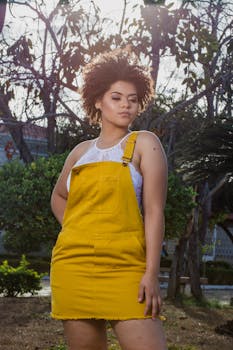 一位时尚的年轻女子身着充满活力的黄色连衣裙，在户外自信地摆出姿势