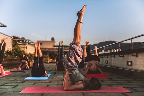 Free Group of Women Lying on Yoga Mat Under Blue Sky Stock Photo