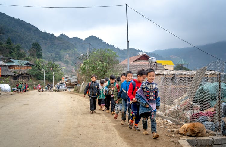 A Group Of Kids Walking At The Side Of The Road 