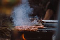 肉串在明火上烤得滋滋作响，烟雾缭绕，尽显户外烹饪的氛围