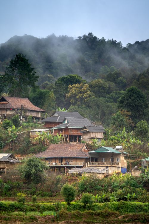 Free Picturesque village nestled in lush hills with misty atmosphere, showcasing rustic architecture. Stock Photo