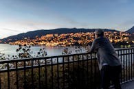 黄昏时分，一位成年男子凝视着海湾畔明亮的城市景观，捕捉到宁静与风景之美