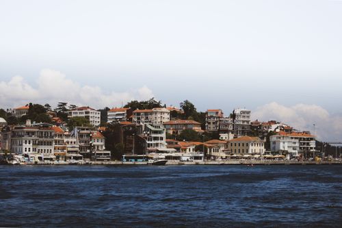 Free Picturesque coastal town with a harbor, featuring docked boats and charming waterfront buildings under a clear sky. Stock Photo