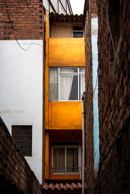 Vertical view of vibrant residential building facade with white and yellow walls, emphasizing urban architecture.
