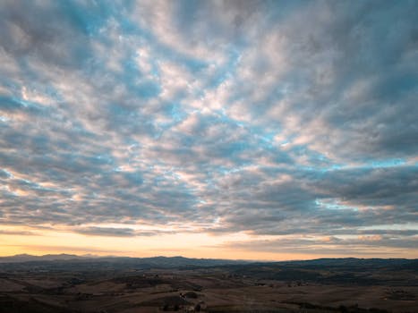 Expansive landscape view under a dramatic cloudy sky at sunset.
