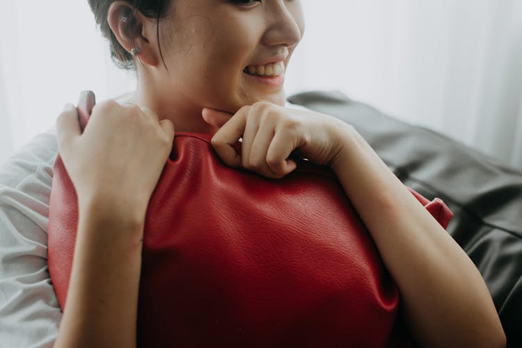 A Girl Smiling While Hugging A Red Pillow