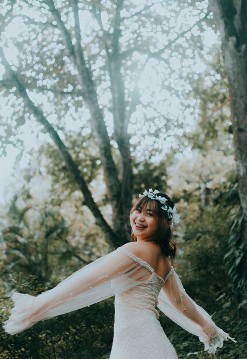 Free Smiling woman in white dress with flower crown twirling outdoors. Stock Photo