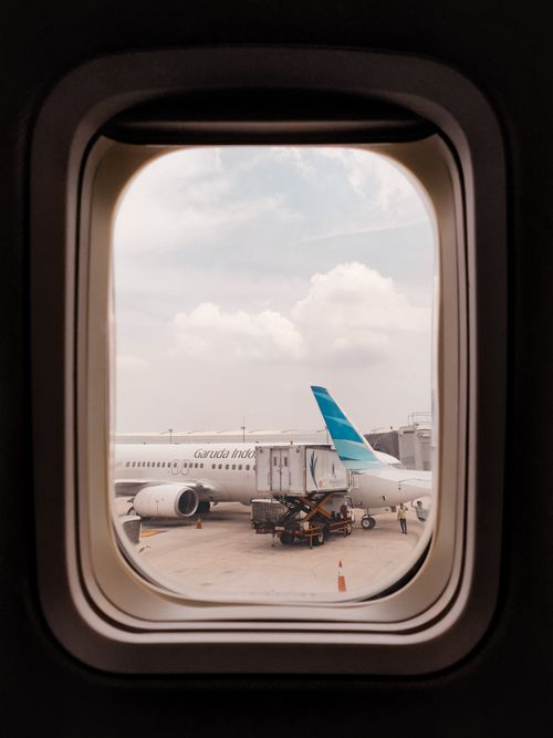 Free Airplane parked at an airport terminal viewed through a cabin window. Stock Photo
