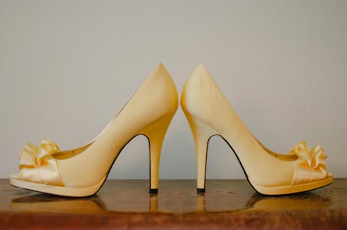 Pair of Women's Beige Peep-toe Heeled Sandals on Wooden Surface