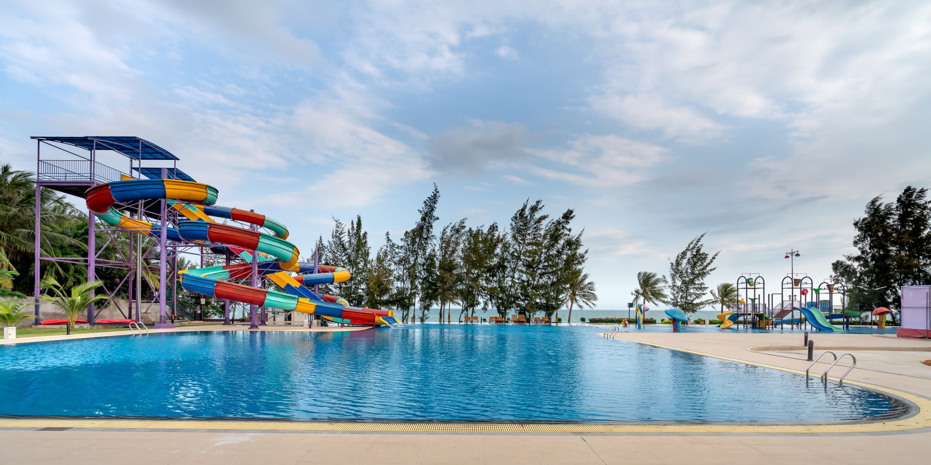 Serene water park view with vibrant slides and lush trees.