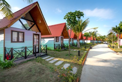 Free Colorful bungalows in a lush, tropical garden setting under clear blue skies, perfect for a relaxing resort stay. Stock Photo