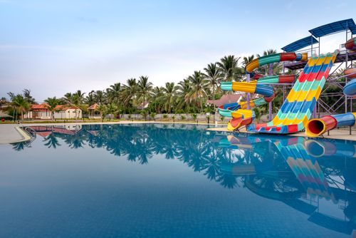 Free Colorful water slides and a serene pool at a summer water park for relaxation and fun. Stock Photo