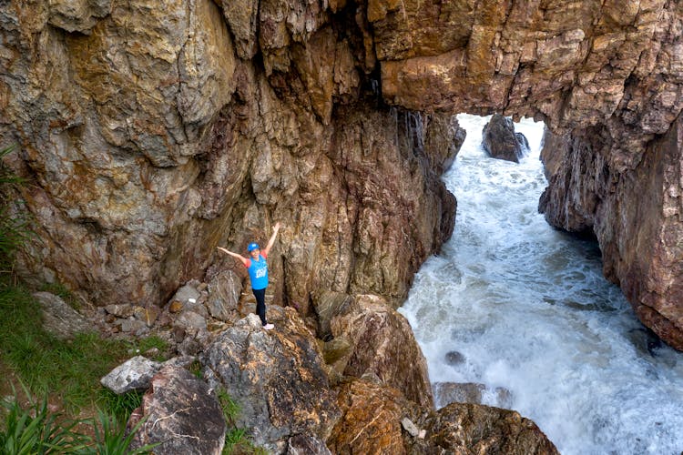 Happy Person With Arms Raised On Rocks Near Stream