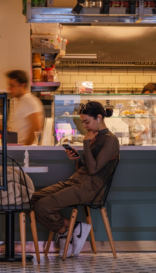 Woman with Smartphone Sitting in Restaurant