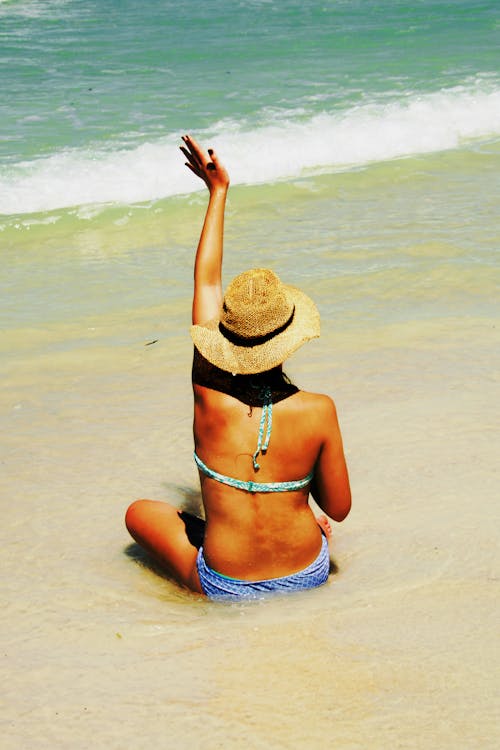 Woman Sitting on Shore Waving Hands