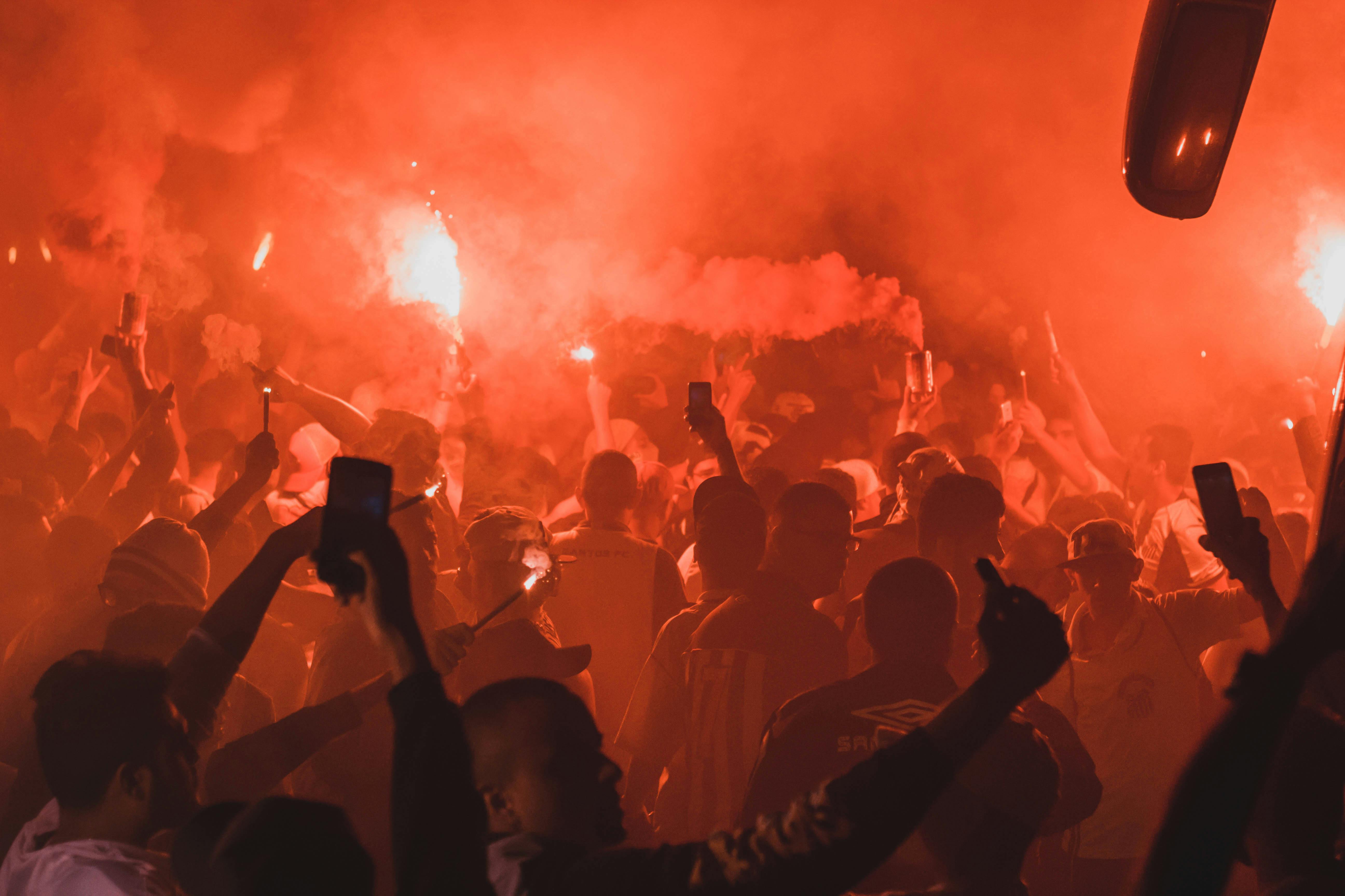 Crowd holding flares. | Photo: Pexels
