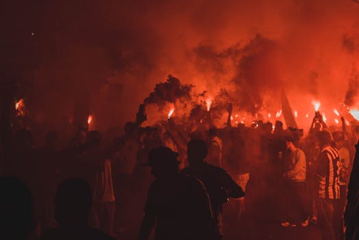 这是一场充满活力的夜间庆祝活动，人们手持照明弹，在烟雾与鲜艳的火焰中欢庆
