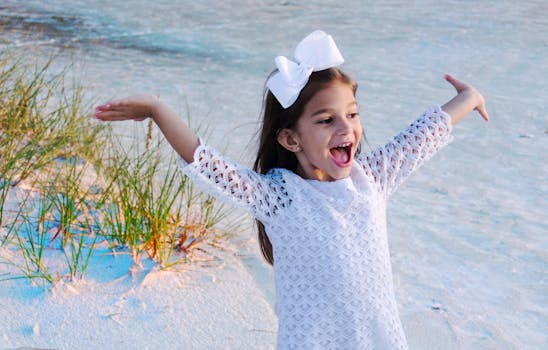 一个快乐的女孩身着白色连衣裙，在佛罗里达州萨拉索塔的海滩上玩耍