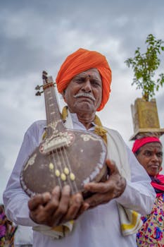 Elderly man in traditional attire holding a string instrument in Pandharpur, India.
