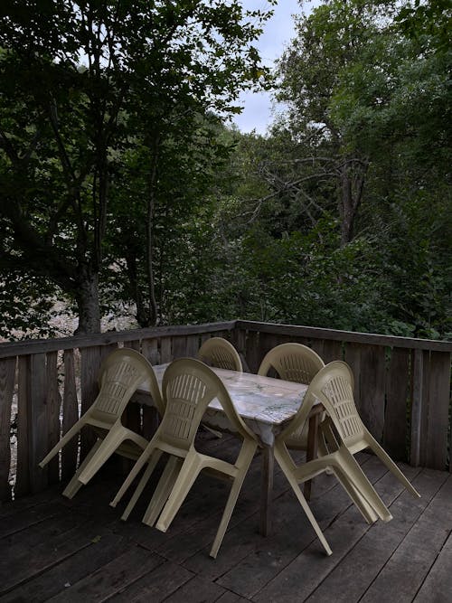 A Plastic Chairs on the Table Near the Wooden Railing at the Terrace