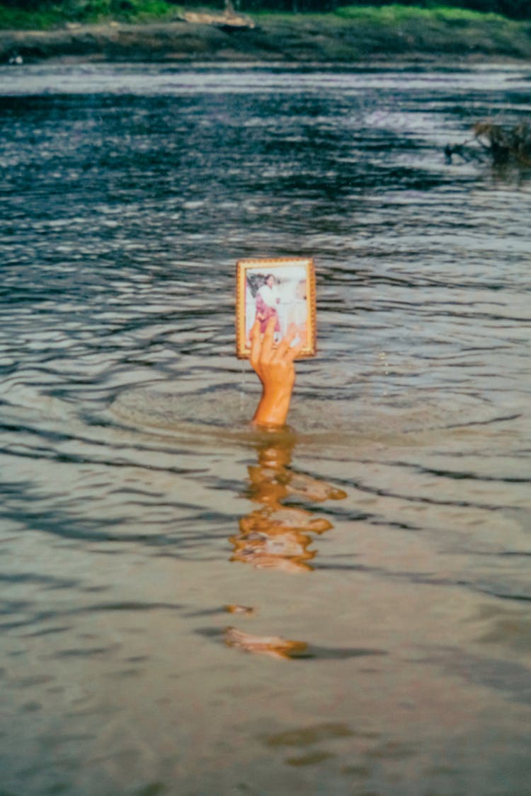 Hand Sticking Out Of The Water Holding A Picture 