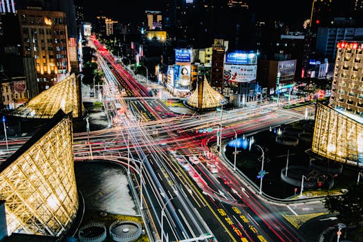 Dynamic aerial view of a bustling city intersection at night with colorful light trails from traffic.