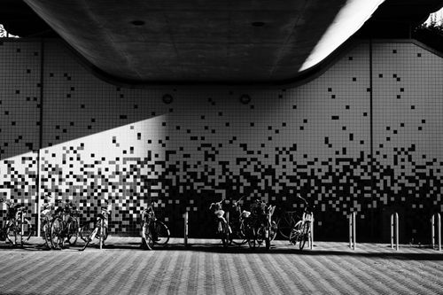 Free Artistic black and white image of bicycles against a tiled pixelated wall under an overpass. Stock Photo