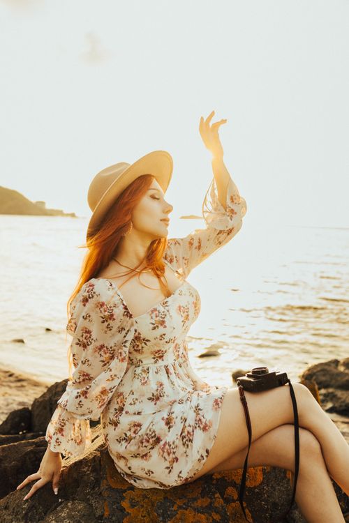 Free A serene moment by the sea, capturing a woman in a sunhat enjoying the sunset. Stock Photo