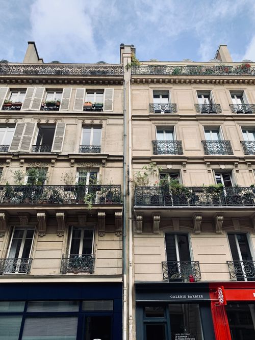 Free Elegant Haussmann-style facade in Paris with window shutters and wrought iron railings. Stock Photo