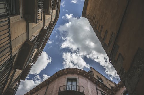 Low Angle Photography of Brown Concrete Buildings Under Blue Sky and White Clouds