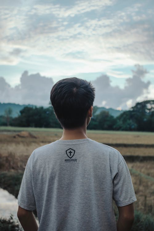 A Back View of a Man in Gray Shirt Standing on the Field