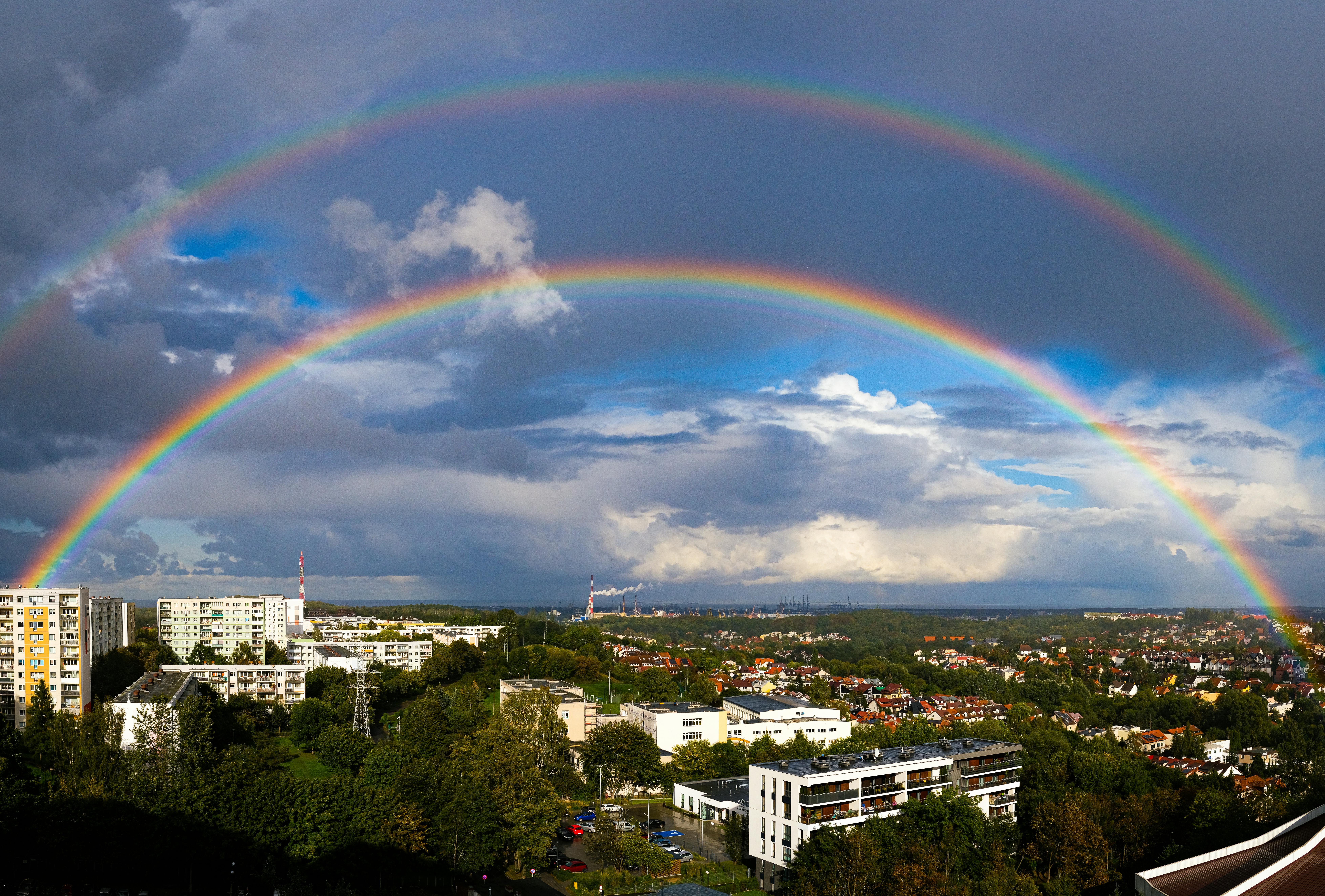 A stunning aerial view of a double rainbow over Gdańsk's urban landscape.