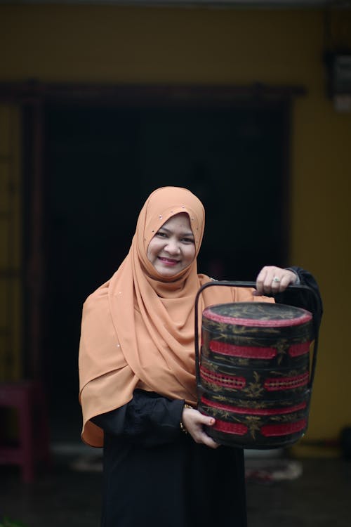 Smiling Woman in Hijab Standing with Item