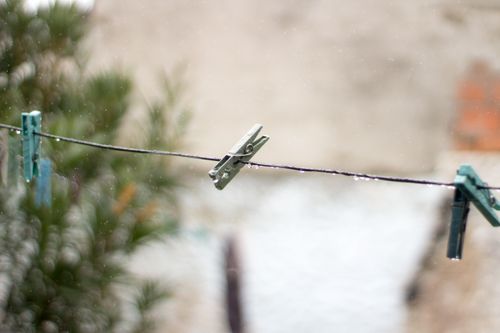 Free Close-up of clothespins hanging on a wet clothesline outdoors with blurred background. Stock Photo