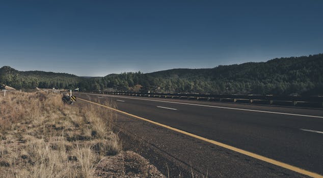A highway winding through lush forested mountains under a clear blue sky.