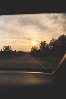 A serene road trip view with a beautiful sunset captured from a car window, emphasizing tranquility and adventure.