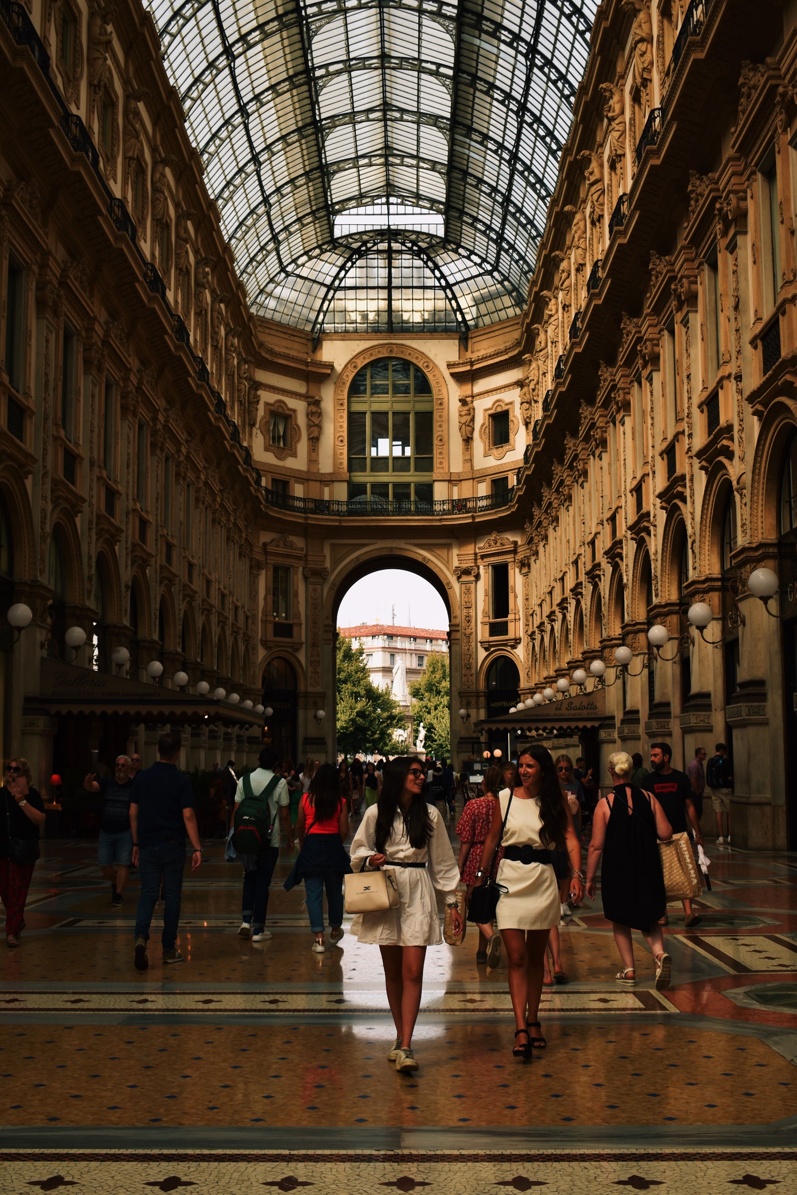 People strolling under the grand architecture of Galleria Vittorio Emanuele II in Milan.