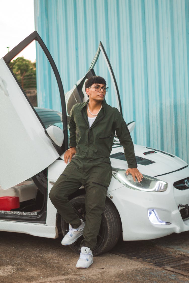 A Man With Eyeglasses Posing On A White Car