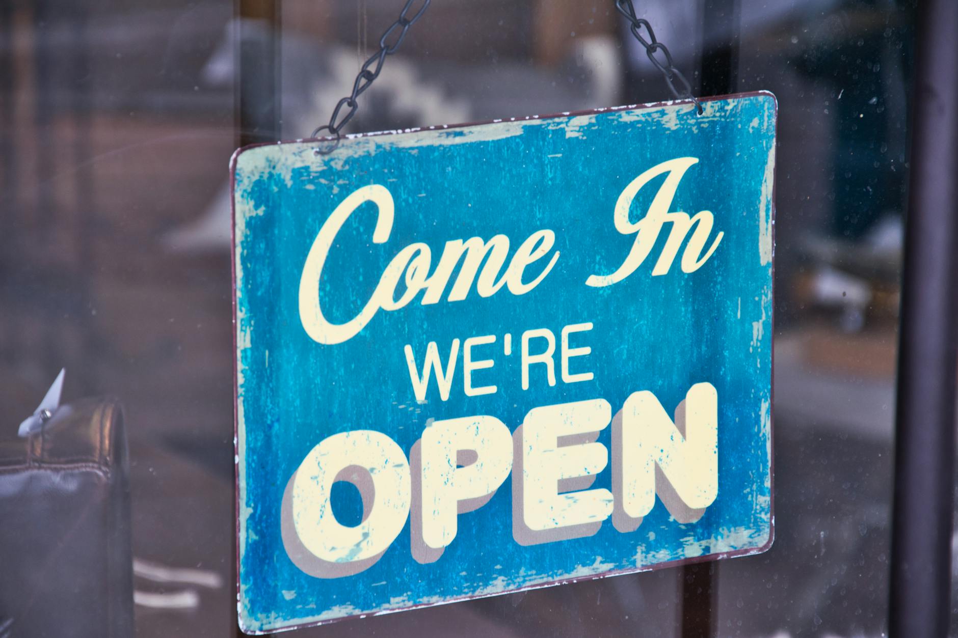 Retro blue open sign on a shop glass door inviting customers in.