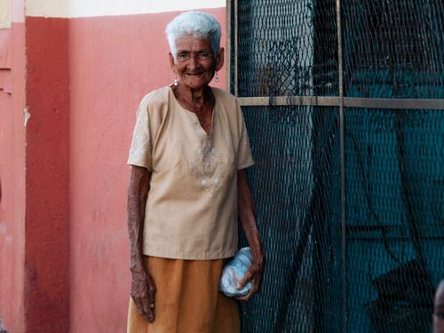 Free Smiling senior woman standing outdoors against a colorful wall. Stock Photo