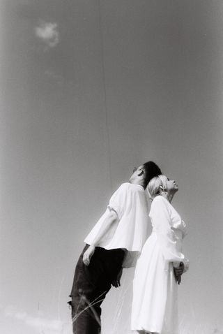 Couple photographed back to back against the sky — photo by anait film on Pexels