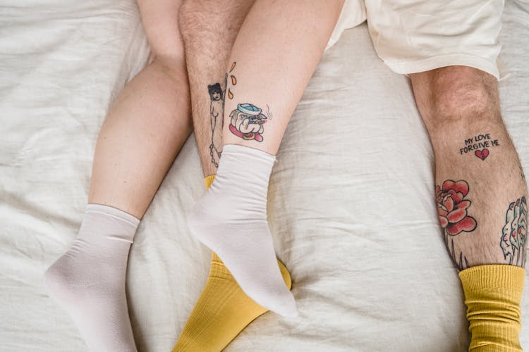 Couple Legs With Tattoos In Bed